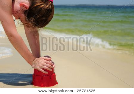 Młoda dziewczyna zamek budynku piasku na plaży
