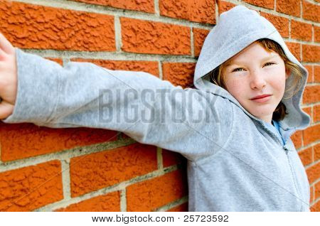 Young girl in hoodie against brick wall