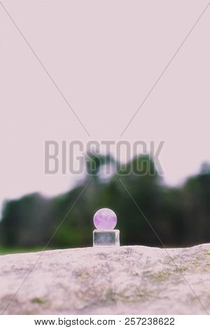Close Up Of An Amethyst Crystal Ball On Rocky Terrains.