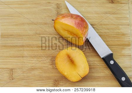 An Amigo Pluot Chopped In Half Atop A Wood Cutting Board