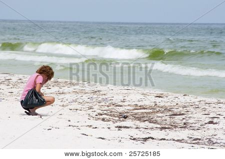 เพนซาโคลาบีช - 23 มิถุนายน: มี unidentifed crouches beachgoer ติดน้ำมันครอบคลุมทรายบน 23 มิถุนายน 2