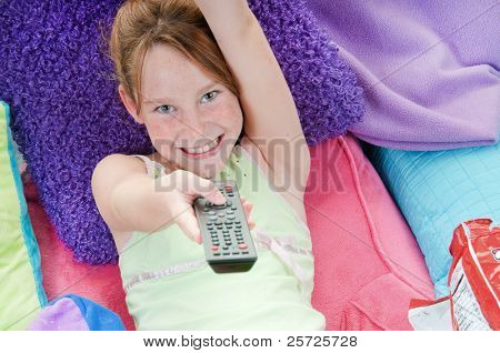 Chica joven con chips en la cama viendo la televisión