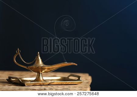 Aladdin Lamp Of Wishes On Wooden Table Against Dark Background