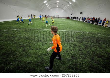 Boy goalkeeper at goal box during soccer game, side view.