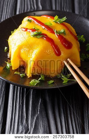 Asian Omelette With Rice, Chicken And Vegetables Served On A Black Plate On A Table. Vertical