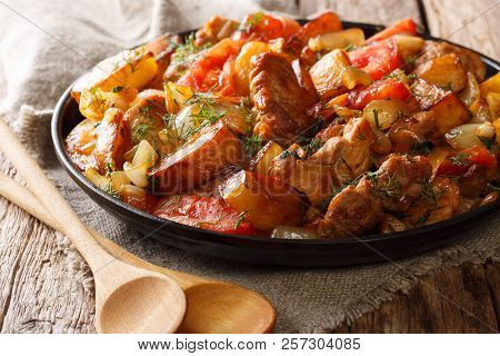 Home-style Food: Fried Meat With Potatoes, Tomatoes, Onions, Herbs And Spices Close-up On A Frying P
