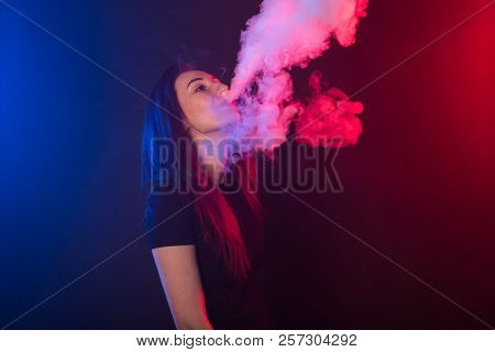 Portrait Of Asian Woman Smoking Vape Or E-cigarette In Neon Light At Black Background.