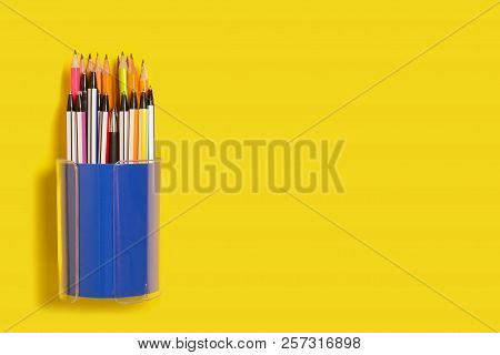 New Bright Colored Pens Lying In A Purple Penholder On A Yellow Background. Concept Of Office Suppli