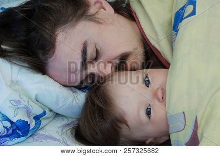Little Baby Girl Wake Up In The Morning. Parent Tired Sleeping. Father Lying On Bed. Happy Family.