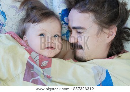 Little Baby Girl Wake Up In The Morning. Parent Tired Sleeping. Father Lying On Bed. Happy Family.