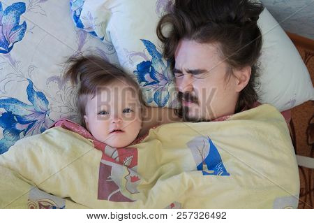 Little Baby Girl Wake Up In The Morning. Parent Tired Sleeping. Father Lying On Bed. Happy Family.