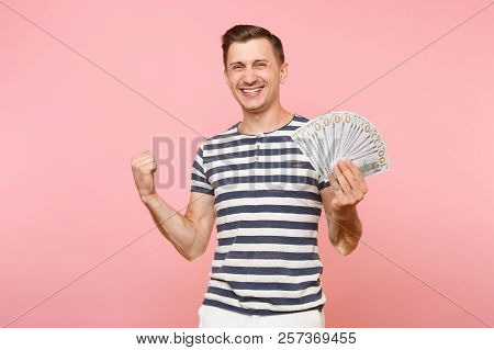 Portrait Of Smiling Excited Young Man In Striped T-shirt Holding Bundle Lots Of Dollars, Cash Money,