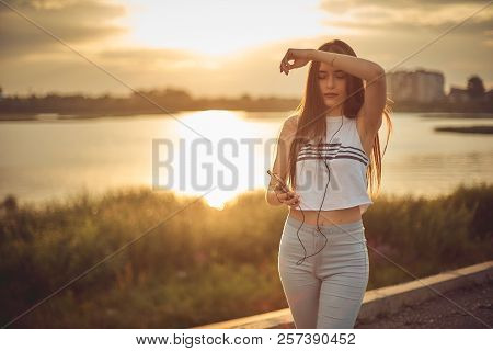 Young Beautiful Caucasian Girl Listening To Music With Smartphone Walking In The City With Headphone