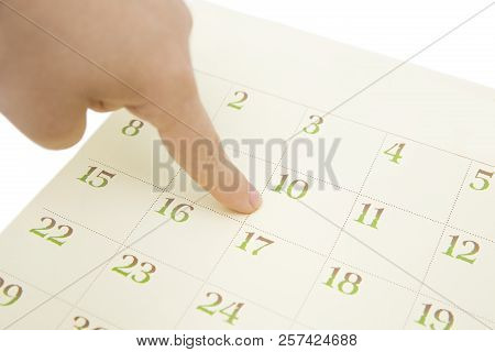 Female's Finger Showing Date In A Calendar On White Background. Number In The Calendar
