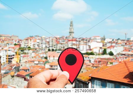 closeup of the hand of a young caucasian man with a red marker pointing the old town of Porto, in Portugal, highlighting the Torre dos Clerigos, the belfry of the Clerigos Church, in the background