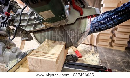 Close Up Of A Carpenter In Work Clothes Working In Woodwork Workshop,  Using Circular Saw For Wood, 