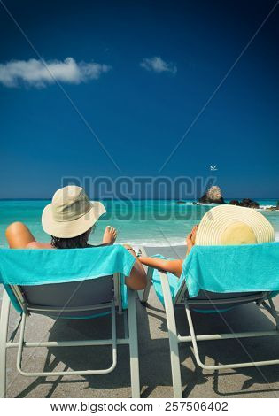 Couple on sunbeds relaxing at the beach in Lefkada Greece