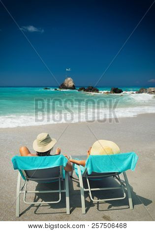 Couple on sunbeds relaxing at the beach in Lefkada Greece