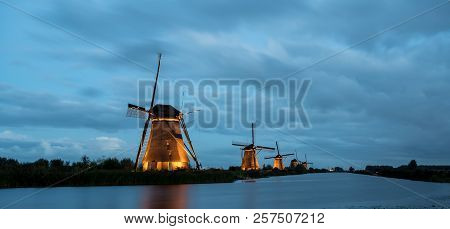 These Beautiful Windmills In Kinderdijk Are Illuminated With White Light At The Blue Hour