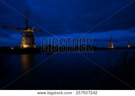 These Beautiful Windmills In Kinderdijk Are Illuminated With White Light At The Blue Hour