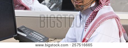 Portrait Of A Smiling Middle Eastern Employee With Headphones On, In A Call Center