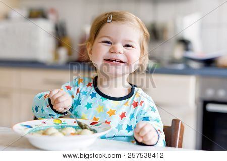 Adorable Baby Girl Eating From Spoon Vegetable Noodle Soup. Food, Child, Feeding And Development Con