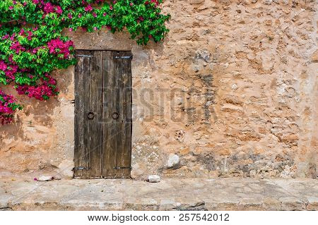 Idyllic Mediterranean Stone House With Old Wooden Door And Bougainvillea