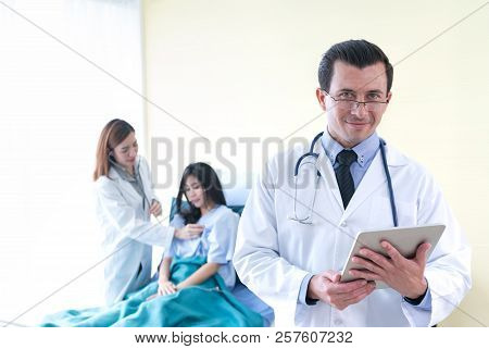 Portrait Of Profressional Doctor With Stethoscope While Female Doctor Take Care Her Patient.