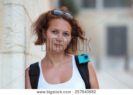 Portrait Of Redhead Woman Traveling With Backpack And Action Camera