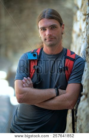Portrait Of Young Man Traveling With His Backpack And Action Camera