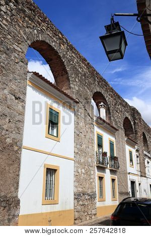 Evora Town In Portugal. Unesco World Heritage Site. Prata Aqueduct With Homes Beneath Arches.