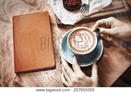 Cup Of Coffee Latte And Red Book On Wooden Table Or Background In Woman Hands From Above.