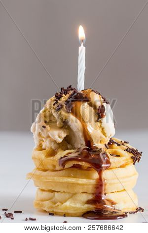 Ice Cream And Waffle Birthday Treat Drizzled With Chocolate Syrup And Sprinkles With One Lit Candle 