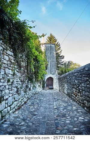 A Old Stone Pavement. A Road Leading To A House With Wooden Gates