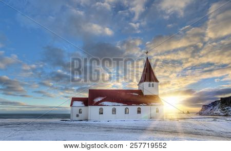 Typical red colored wooden church in Vik town, Iceland in winter. Sunrise light