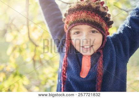 Boyl laughing and playing with autumn leaves in the park