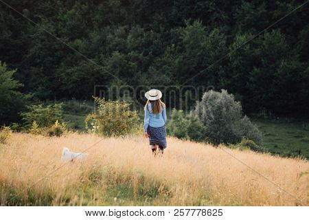 Girl In A Hat Playing With A Dog In The Field At Sunset Sun