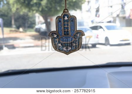 Hamsa Hand Amulet Hanging In The Car, Due To Belief Of Jewish People About Good Luck.