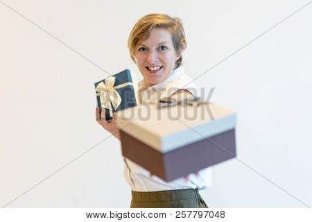 Smiling Pushy Saleswoman Giving Gift Box To Camera. Content Confident Mature Lady Selling Christmas 