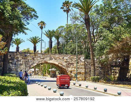 Kos, Greece - July 3, 2018. A Three-wheeler Crossing The Bridge Of Neratzia Castle Of The Knights Of