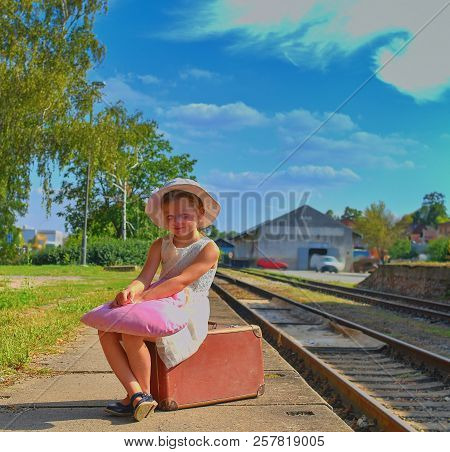 Adorable Little Girl On A Railway Station, Waiting For The Train With Vintage Suitcase. Traveling, H