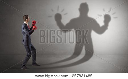 Businessman trying to fight with his unarmed shadow