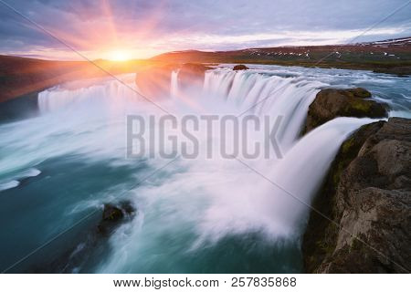Godafoss waterfall. Natural and tourist attraction of Iceland. Rising sun over the cascade and hills