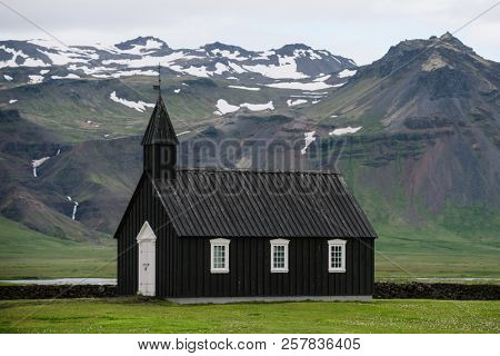 Budakirkja - Black Church. Religious and tourist attraction of Iceland. Summer landscape with a chapel and mountains