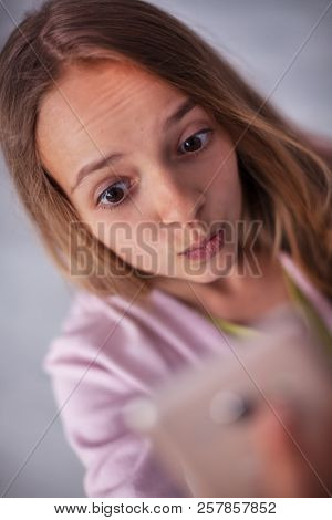Young teenager girl taking a selfie - feeding the social media beast with yet another portrait