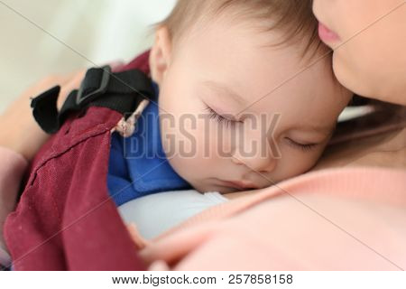 Loving mother with baby in ergo carrier, closeup