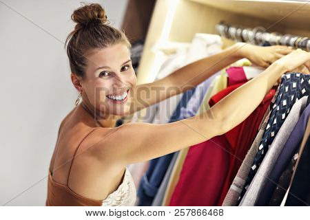 Beautiful woman thinking what to dress in walk-in closet