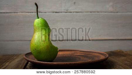 A Bite Pear On A Plate On Wooden Background