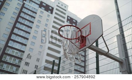 Basketball Ring In The Courtyard Of A Multi-storey Building. A New Basketball Ring With A Net.