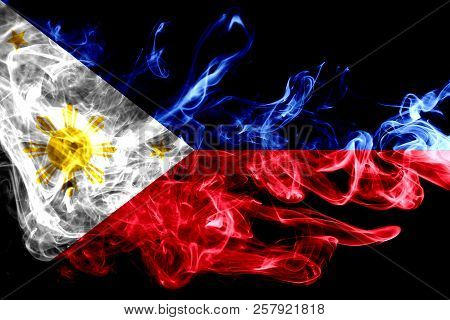 National Flag Of Philipines Made From Colored Smoke Isolated On Black Background. Abstract Silky Wav